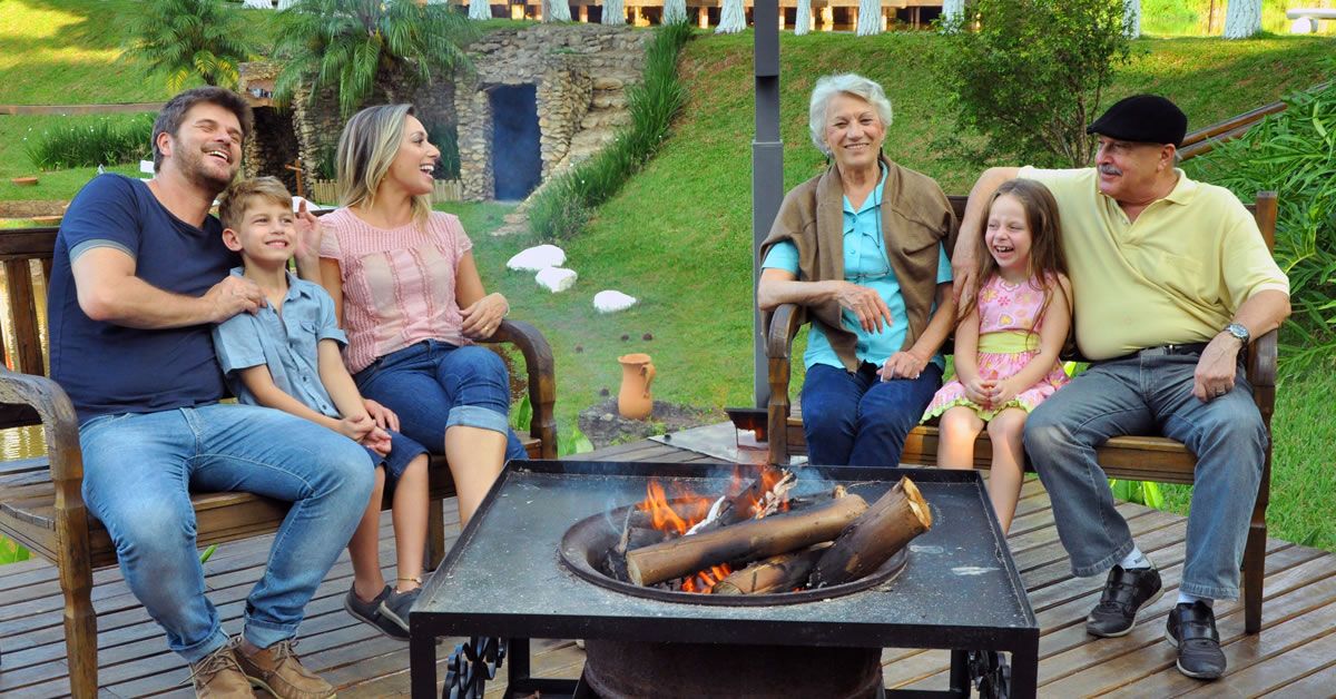 Família reunida em volta de uma fogueira em hotel fazenda, aproveitando a noite em clima acolhedor.
