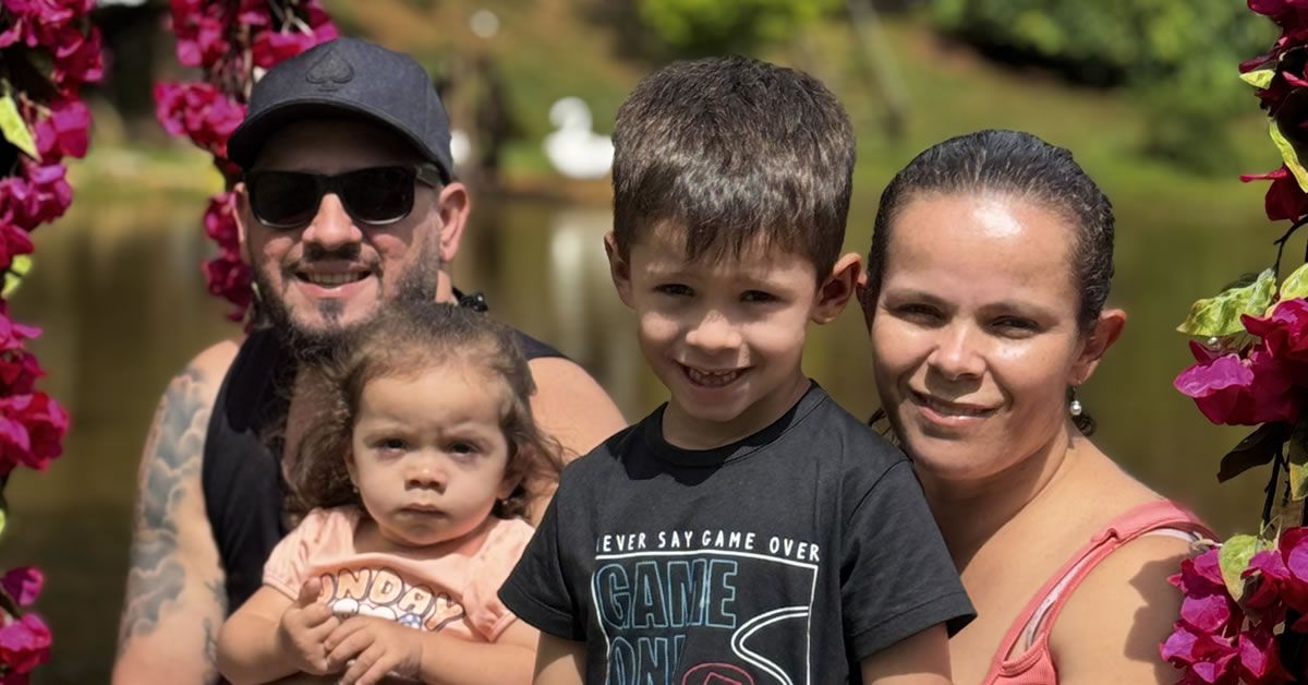 Família sorrindo em frente a um lago ao ar livre.