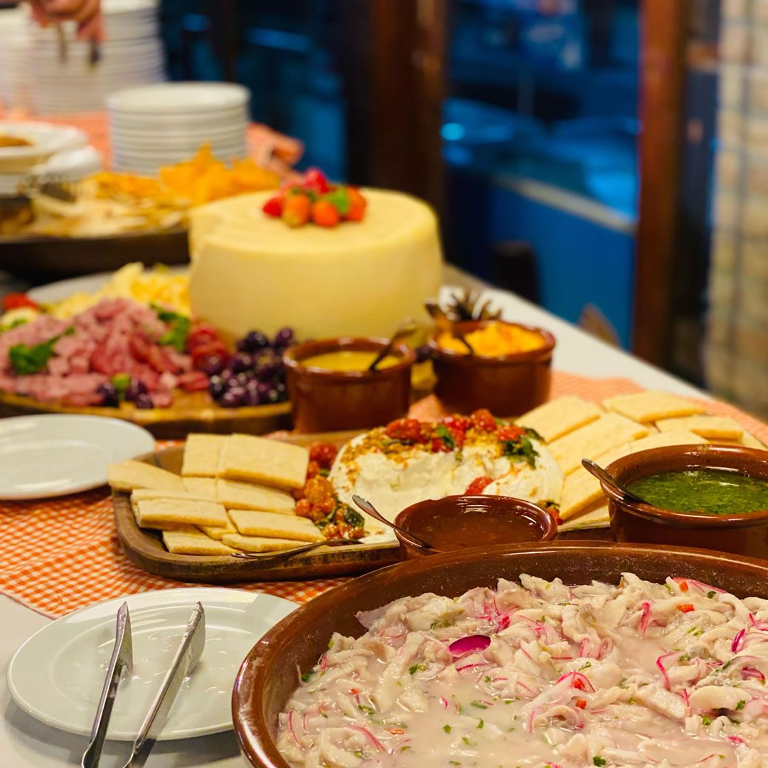Mesa de jantar em um hotel, servida com prato de ceviche fresco decorado com ervas e acompanhamentos.