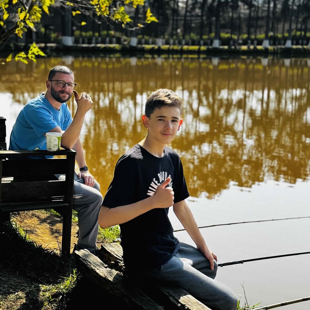 Pai e filho pescando juntos em um lago, compartilhando momento de lazer ao ar livre.