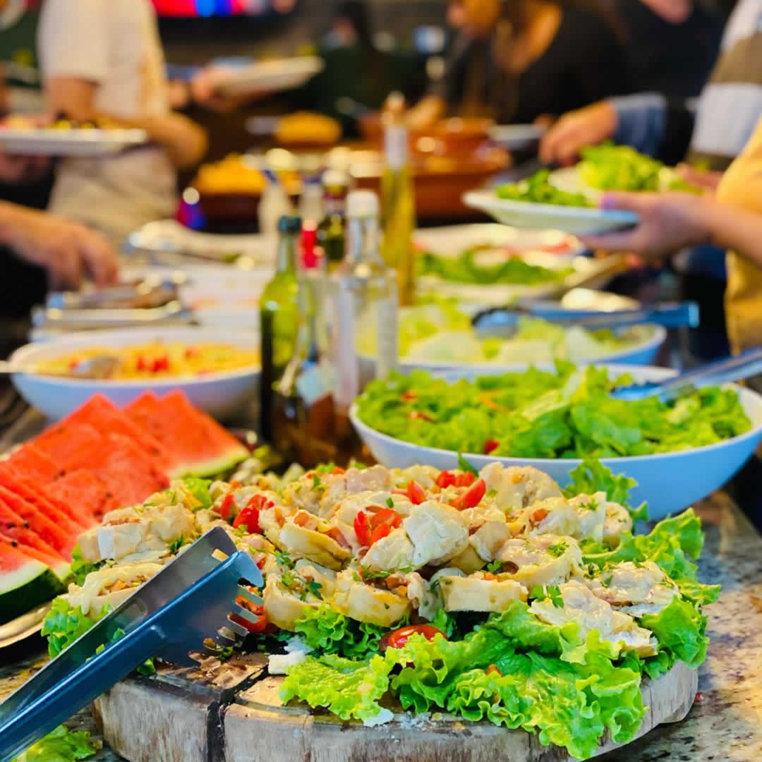 Mesa de jantar em hotel fazenda com pensão completa, servida com prato de peixe grelhado e saladas frescas.