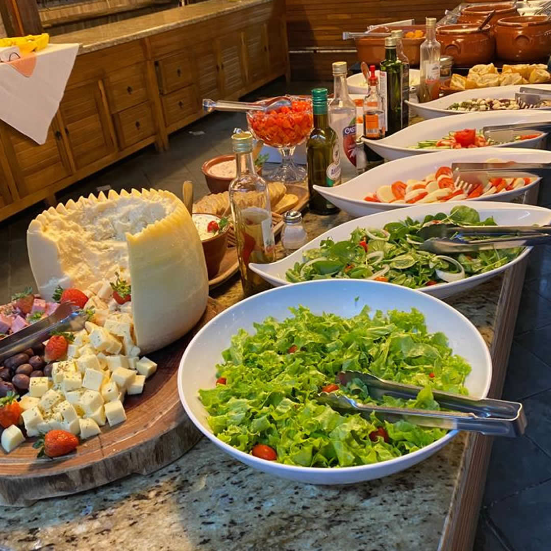 Refeição em hotel fazenda com variedade de saladas frescas servidas à mesa.