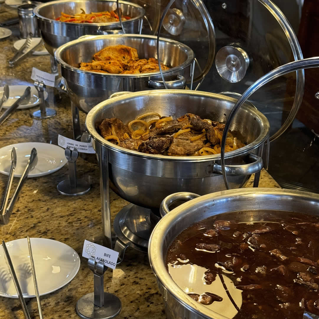 Jantar em hotel fazenda com mesa servida de carnes assadas e acompanhamentos típicos.