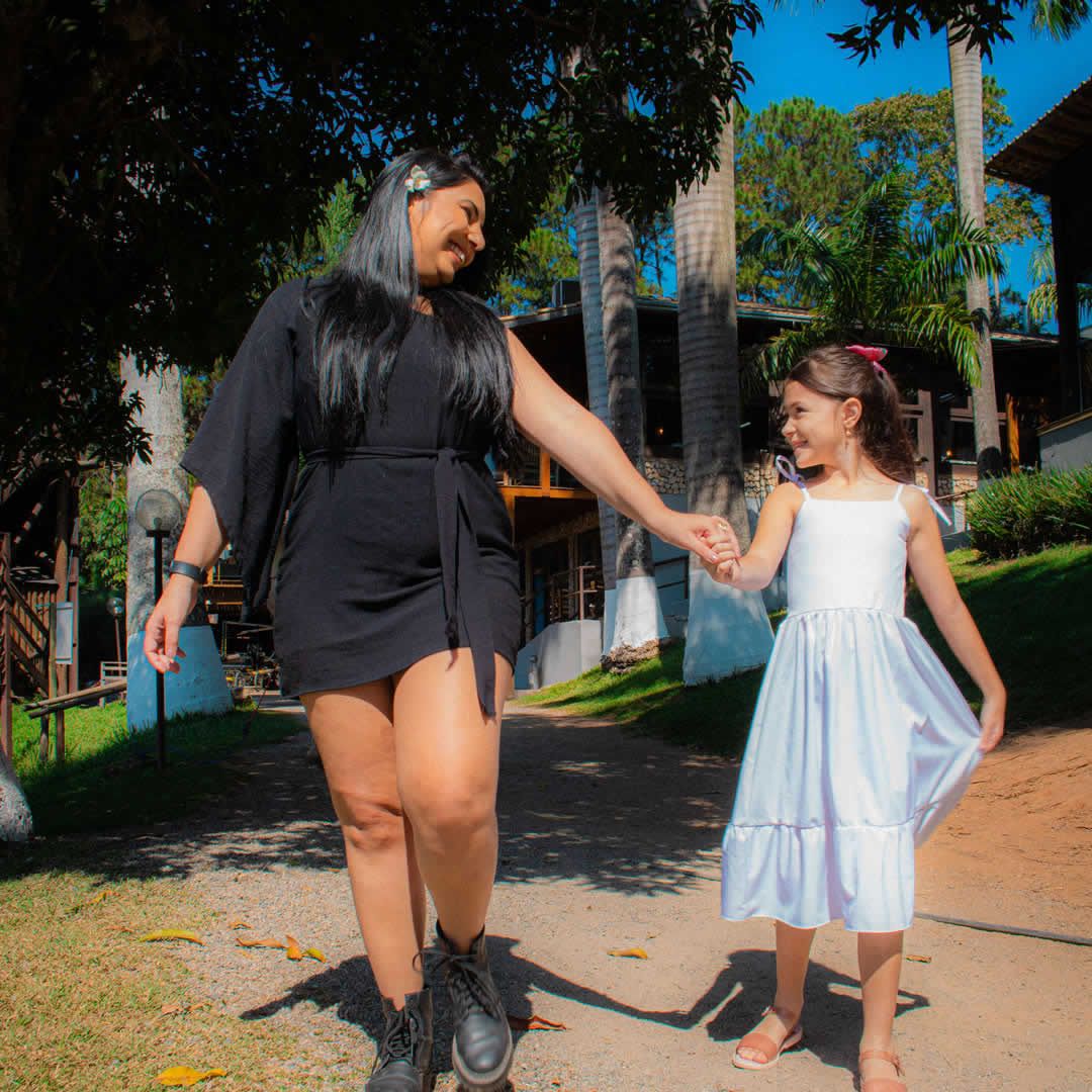 Mãe e filha sorrindo juntas em um hotel fazenda, em um ambiente acolhedor e rodeado pela natureza.