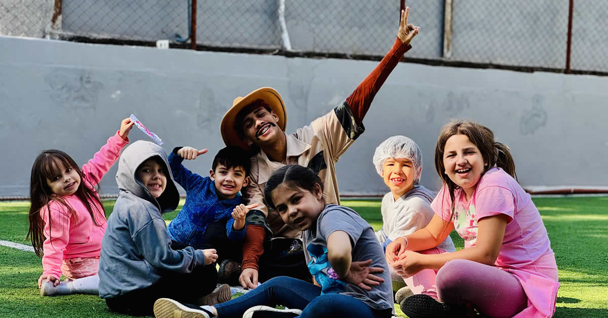 Crianças e recreador de hotel sorrindo para foto