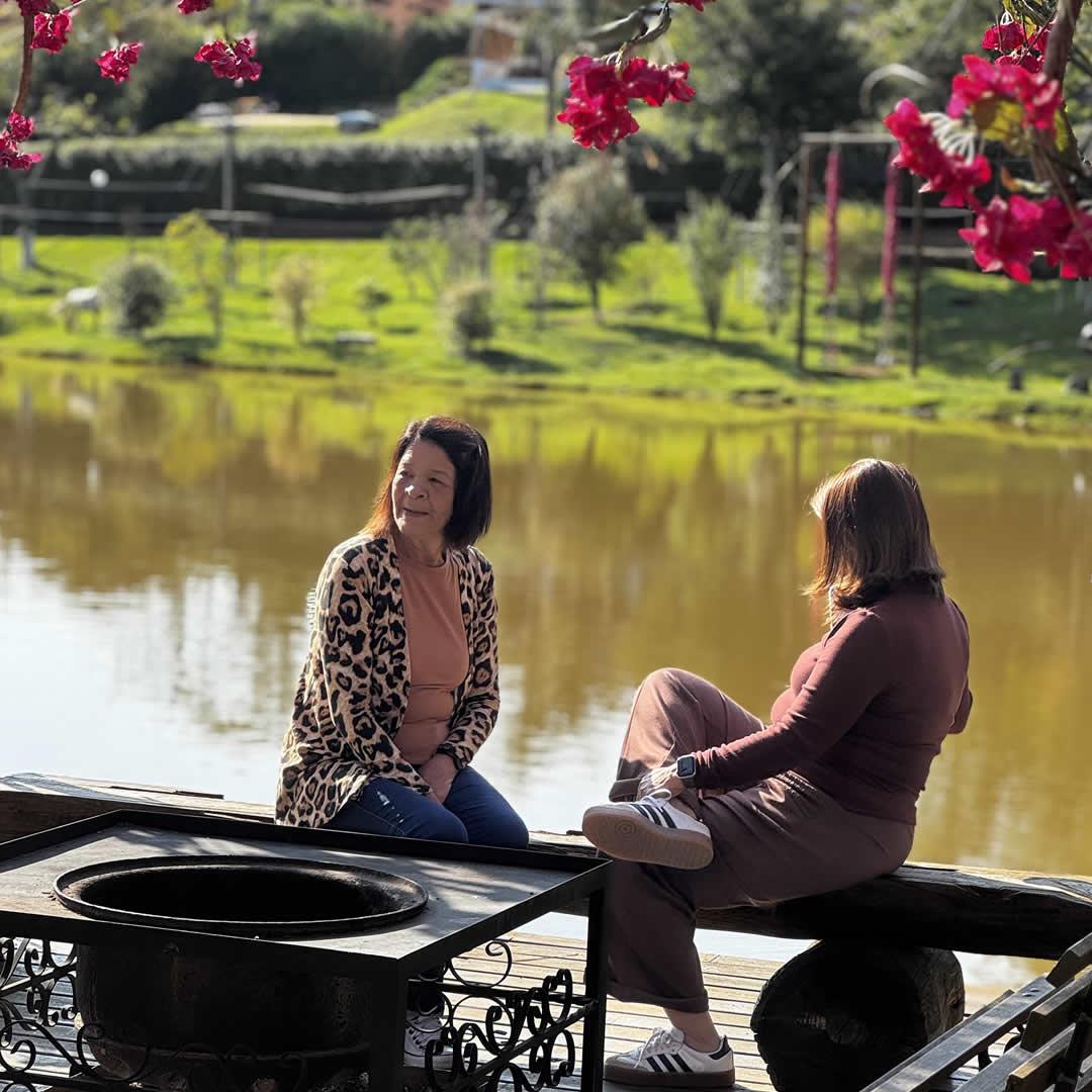 Duas mulheres sentadas em frente ao lago em Hotel Fazenda