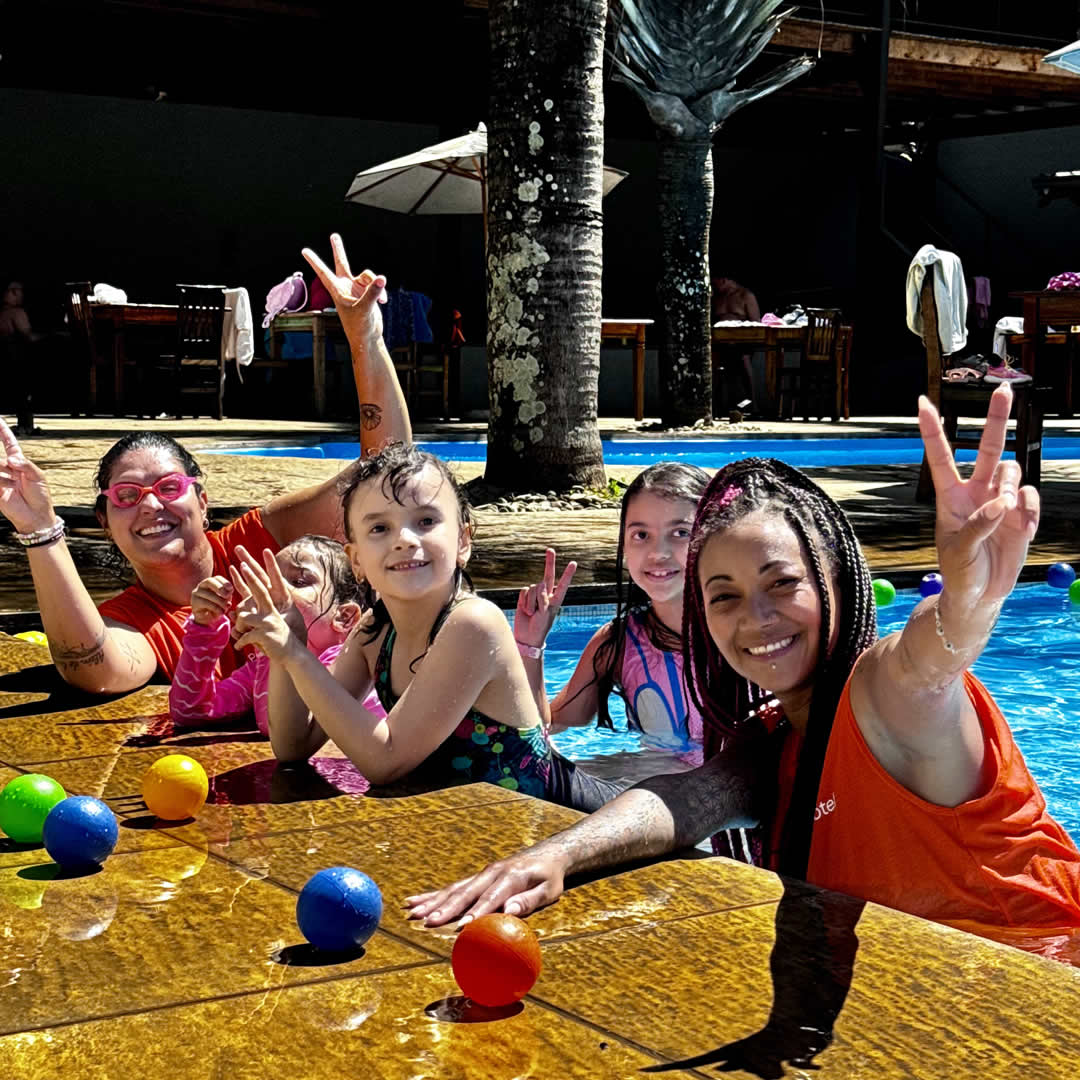 Crianças e recreadores dando risada em piscina