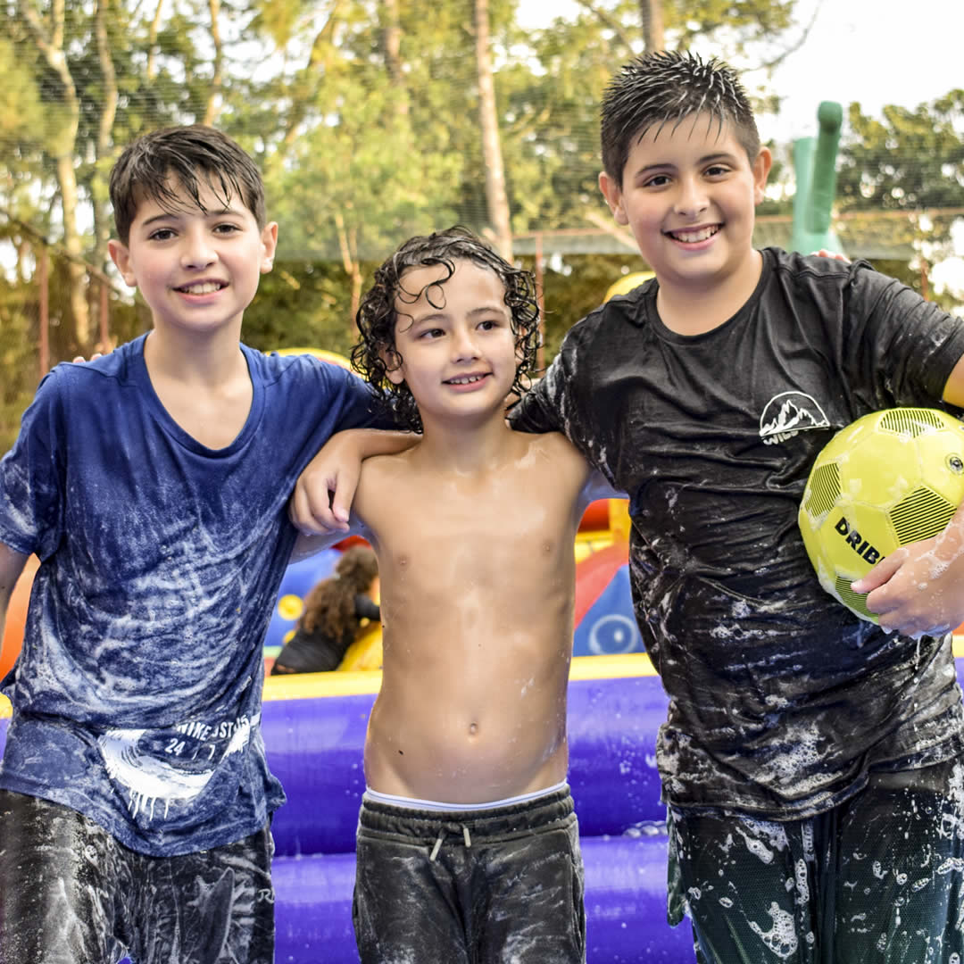 Crianças com uma bola na mão sorrindo para a foto