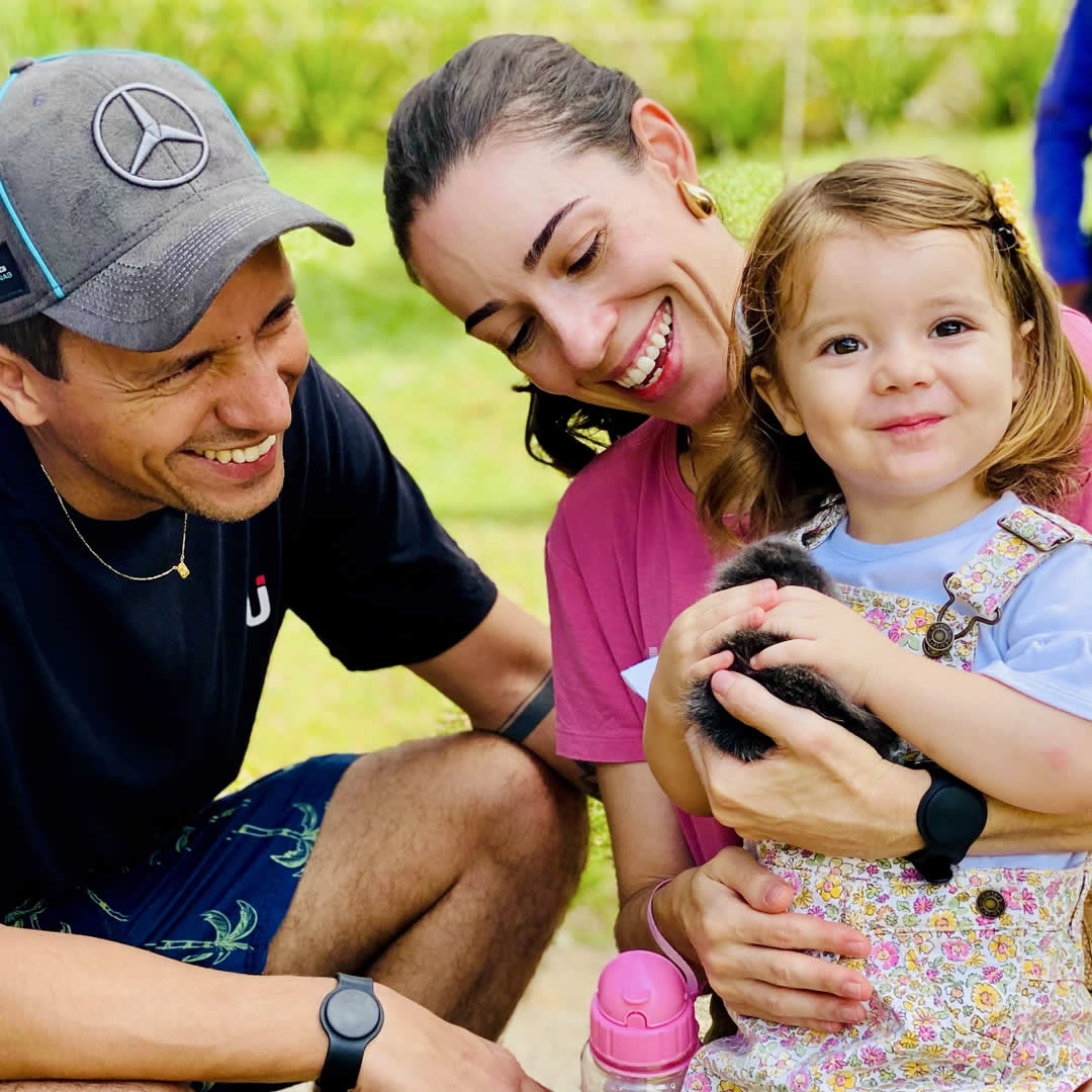 Familia com um coelho na mão sorrindo para foto