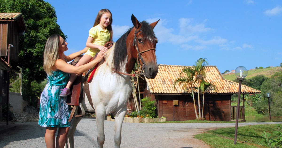 mae ajudando a filha a andar a cavalo no park hotel modelo