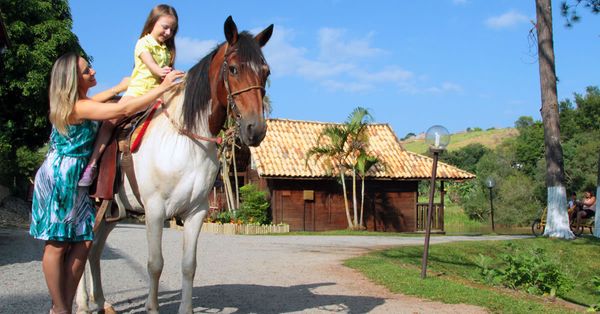 Mãe e filha andando a cavalo em hotel fazenda